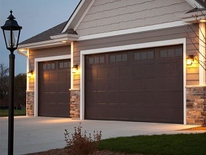 A house with a double- and single-garage door has a mixture of stone and vinyl siding.