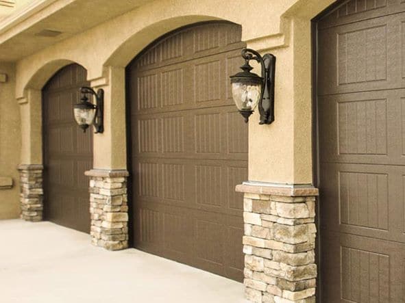 Three brown garage doors on an elegant suburban home